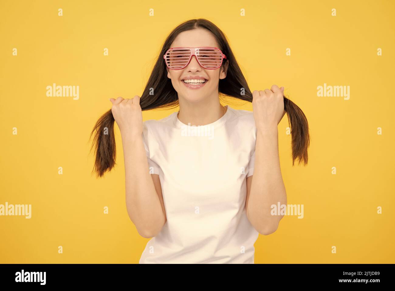 Schönheit lustige Teenager-Mädchen mit Party-Brille, gelber Hintergrund. Überrascht junge Frau mit Spaß Brille. Stockfoto