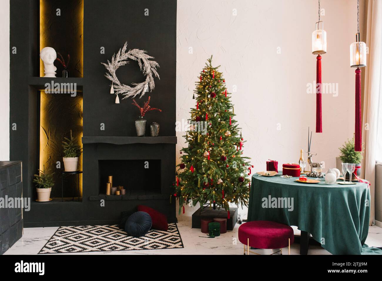 Stilvolles, luxuriöses Interieur des Esszimmers mit einem Weihnachtsbaum. Ein Stuhl neben einem runden Tisch und einem Kamin. Klassisches, modernes Haus Stockfoto
