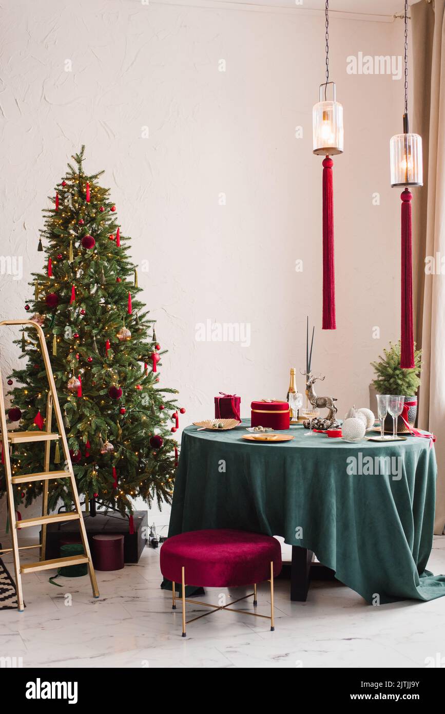 Stilvolles, luxuriöses Interieur des Esszimmers mit einem Weihnachtsbaum. Ein Stuhl neben dem runden Tisch und eine Stuckleiter. Klassisches, modernes Haus Stockfoto