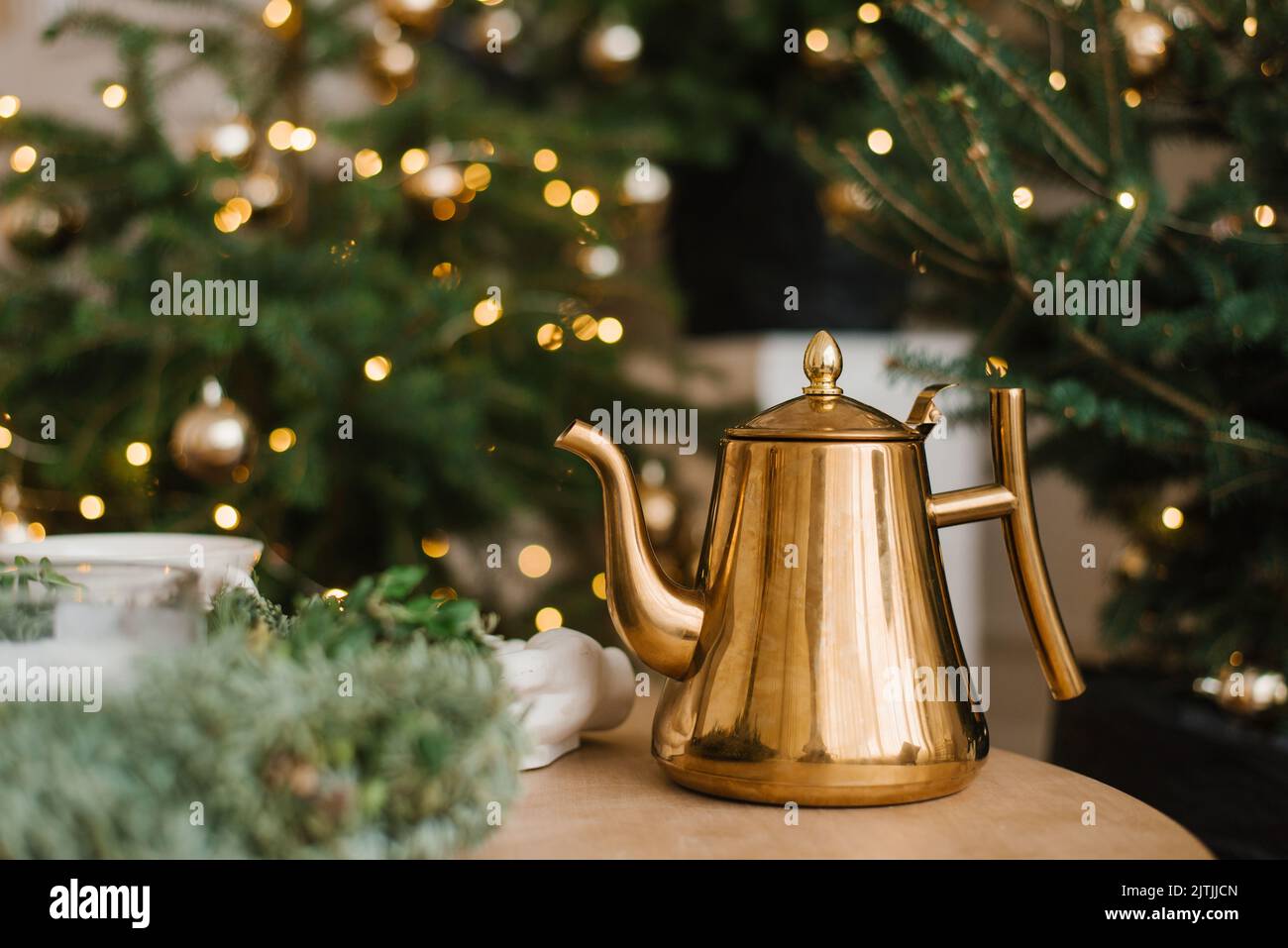 Stilvolle Vintage-Teekannen aus Gold auf dem Tisch vor dem Hintergrund der Weihnachtsbeleuchtung Stockfoto