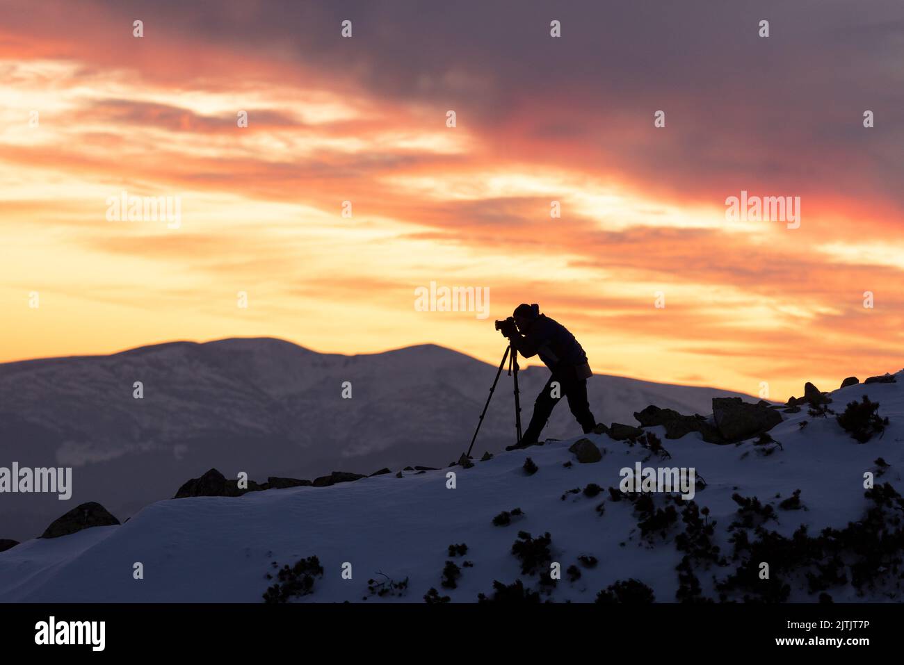 Landschaftsfotograf mit Stativ, der den Blick auf die Berge bei Sonnenuntergang fotografiert Stockfoto