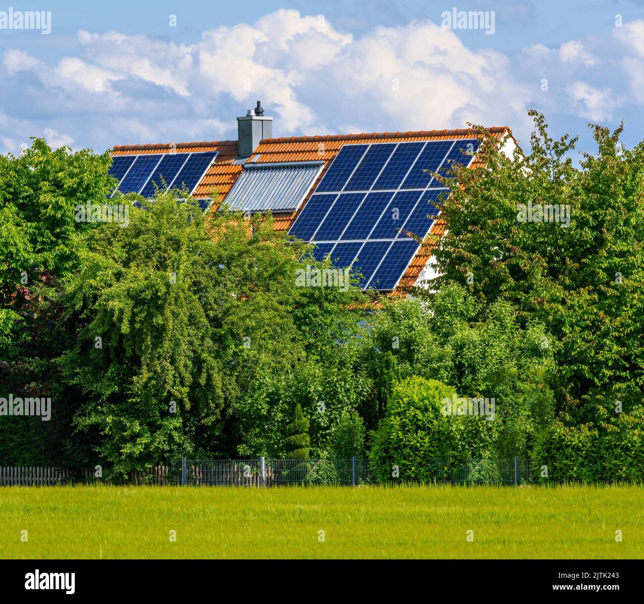 Modernes Haus mit Photovoltaik und Kollektoren für Solarthermie auf dem Dach für die alternative Energieerzeugung Stockfoto