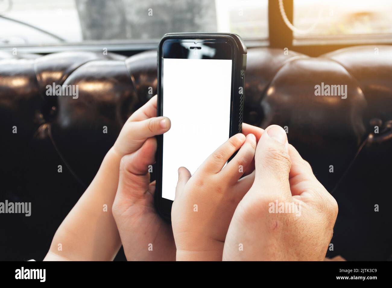 Nahaufnahme der Hände des Mannes, der sein Baby hält, lernt, ein Smartphone zu spielen, leerer Kopierraum-Bildschirm für Text oder Inhalte, modernen Lebensstil und Luxus, sein Stockfoto