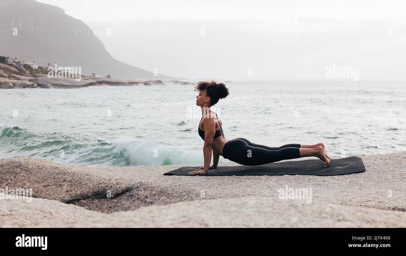 Frau in aufwärtsgerichteter Hundeyogahaltung. Muskulöse Frau, die abends Yoga praktiziert. Stockfoto