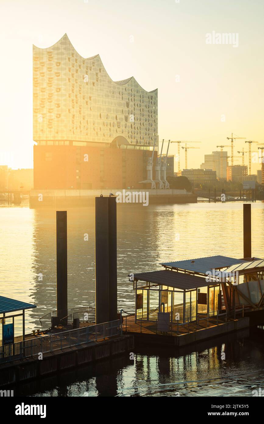 Sonnenaufgang an der Elbphilharmonie, HafenCity und eine Fähranlegestelle an der Elbe im Hamburger Hafen Stockfoto