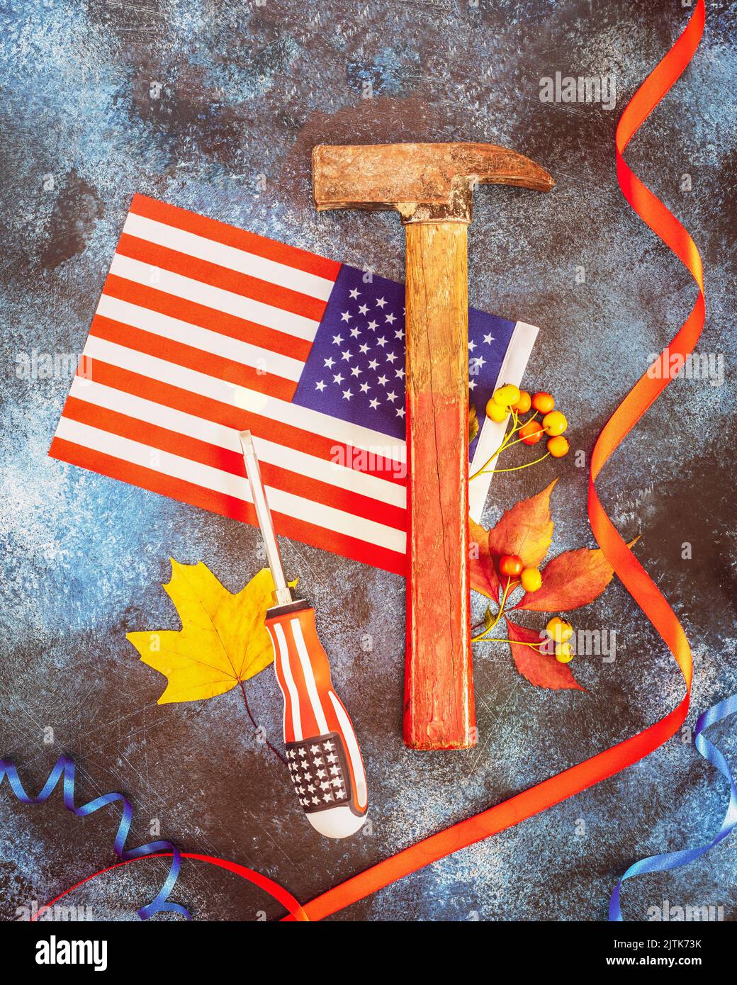 Labor Day Karte mit amerikanischer Flagge, Hammer, Schraubendreher, Herbstblättern und rotem Band auf blauem texturiertem Hintergrund. Labor Day ist Amerika und Kanada tr Stockfoto