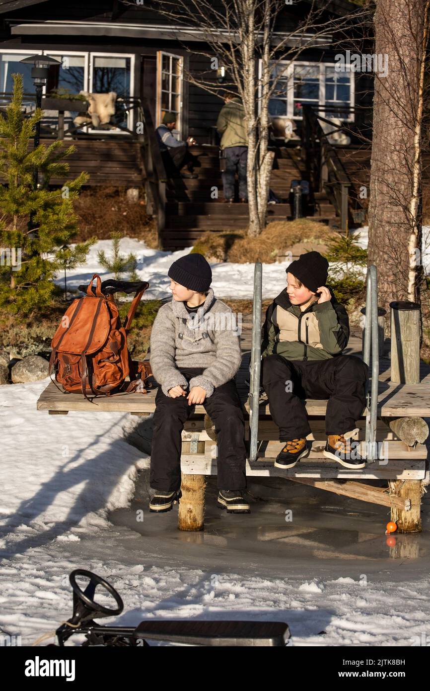 Die ganze Länge der Jungen sitzen zusammen auf dem Steg an sonnigen Tag Stockfoto