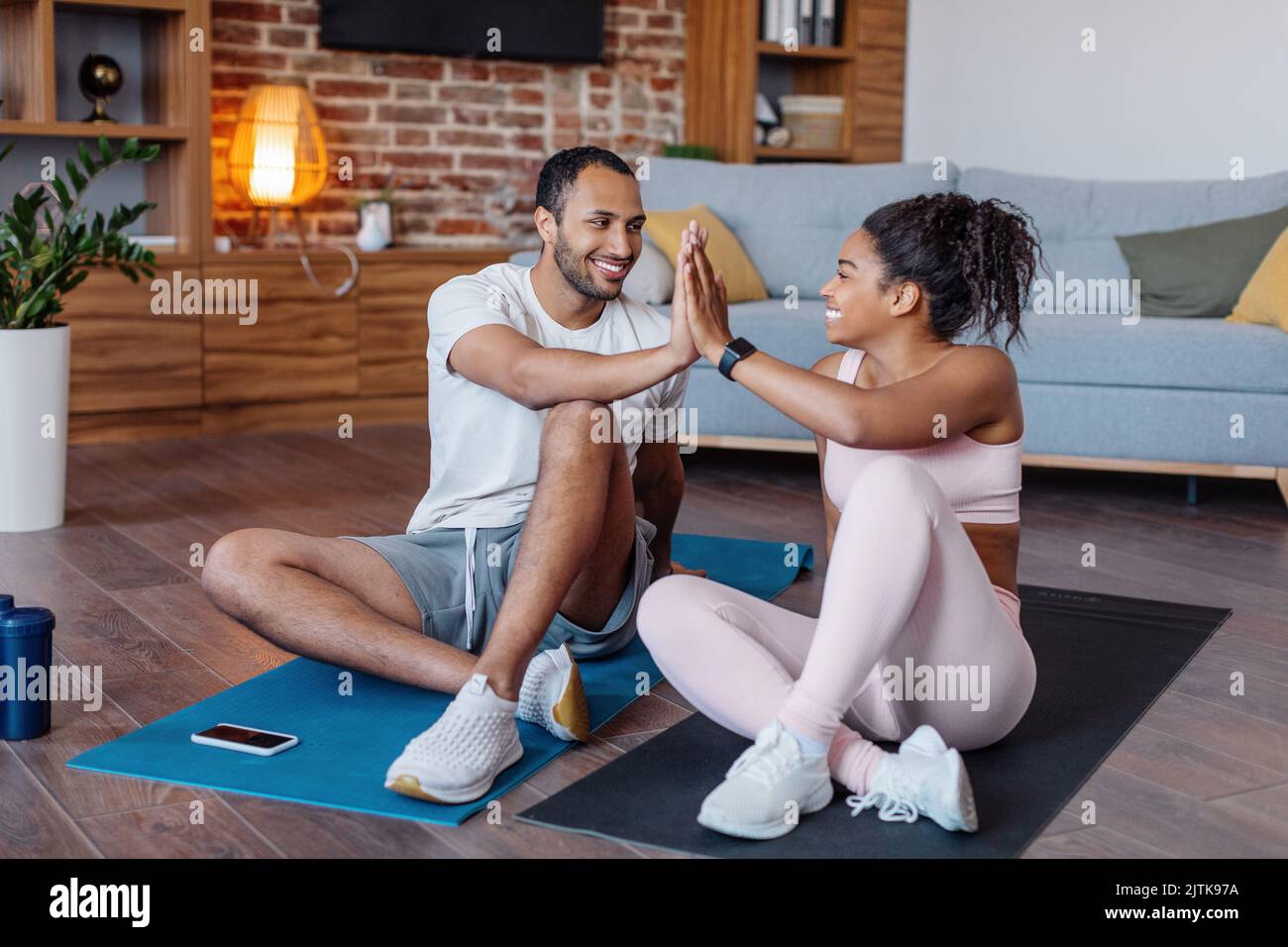 GLAD Millennial african american männlich und weiblich in Sportbekleidung geben hohe fünf für hervorragende Workout-Ergebnis Stockfoto