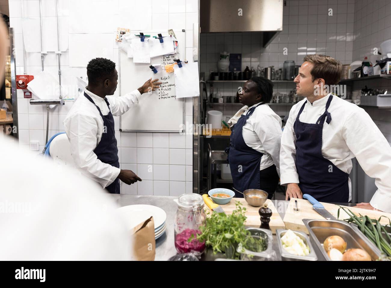 Der Chefkoch erklärt den Kollegen am Whiteboard in der Küche des Restaurants Stockfoto
