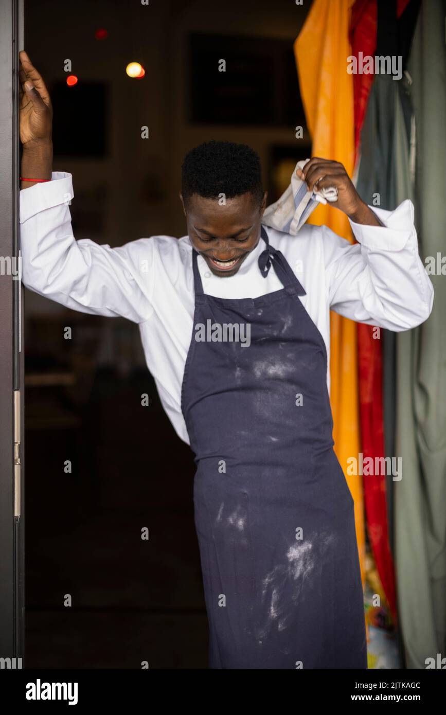 Ein glücklicher Koch, der am Eingang des Restaurants steht und nach unten blickt Stockfoto