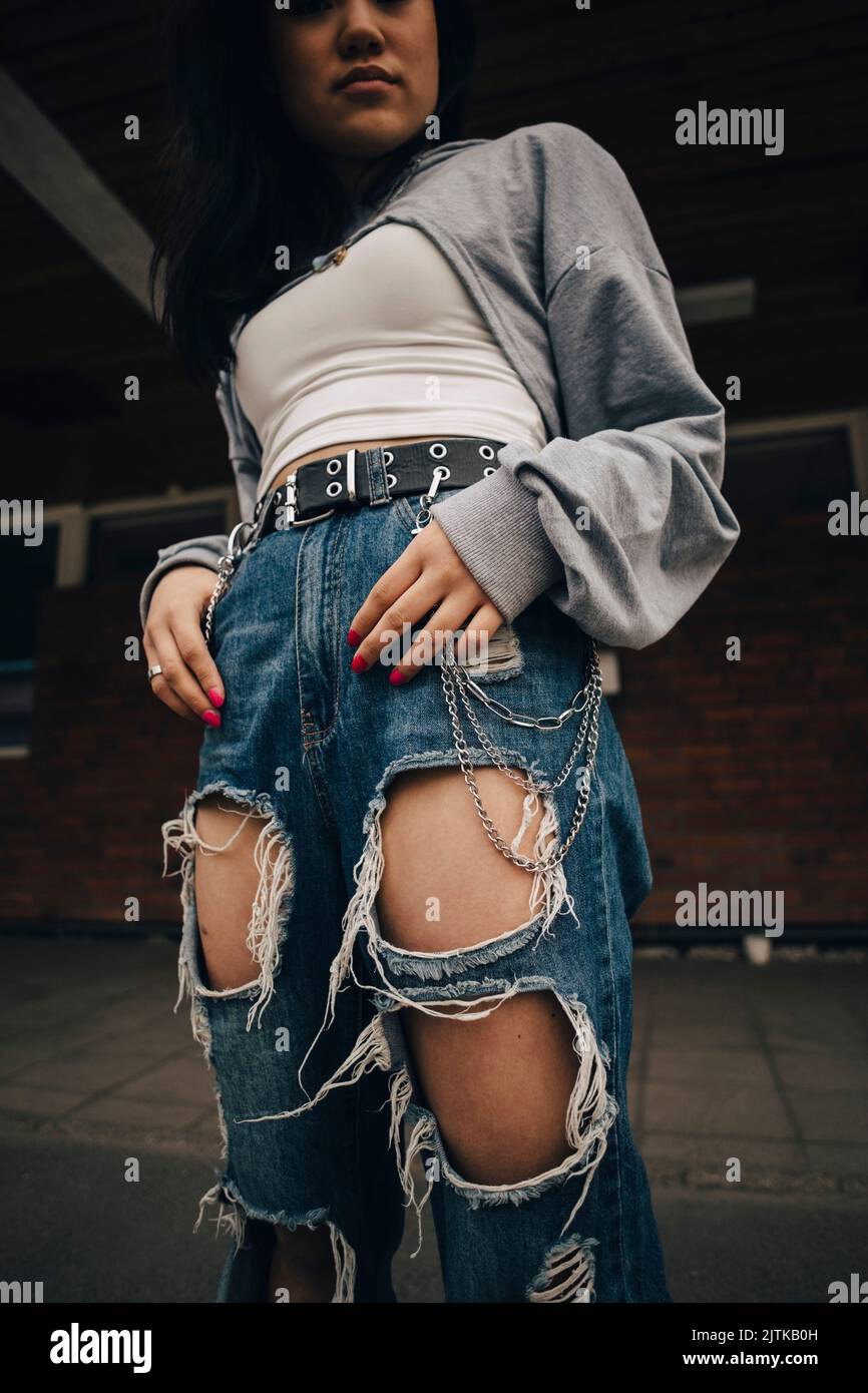 Mittelteil einer jungen Frau in zerrissenen Jeans, die auf dem Fußweg steht Stockfoto