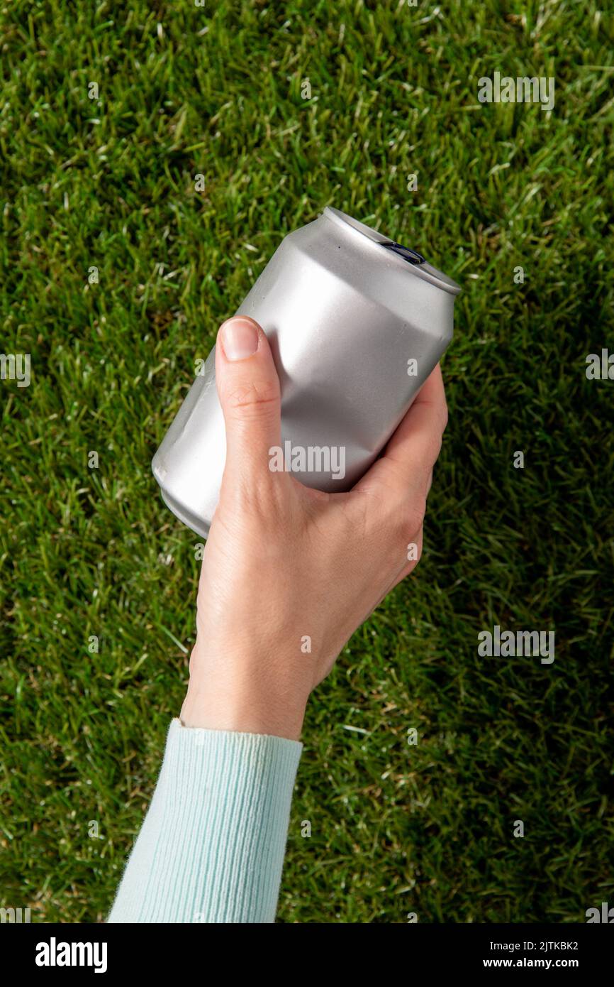 Nahaufnahme der Hand zum Entfernen gebrauchter Blechdosen vom Gras Stockfoto