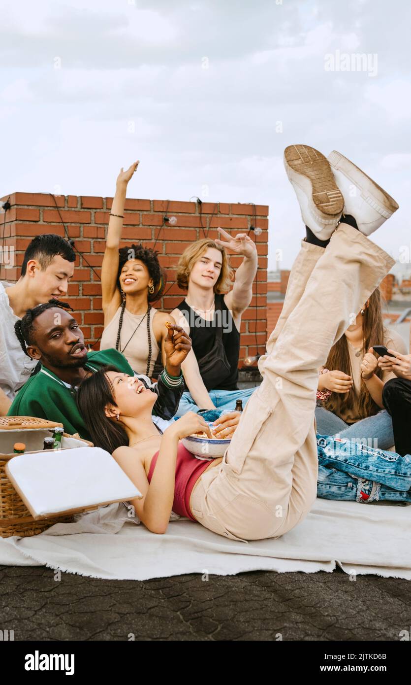 Glückliche männliche und weibliche Freunde genießen zusammen auf dem Dach Stockfoto