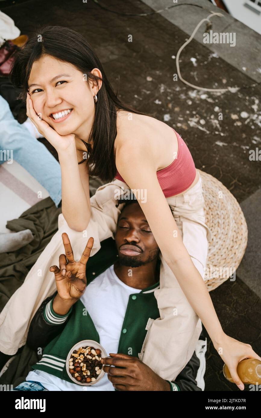 Porträt einer glücklichen jungen Frau mit einem männlichen Freund, der während einer Dachparty das Friedenszeichen gestikuliert Stockfoto
