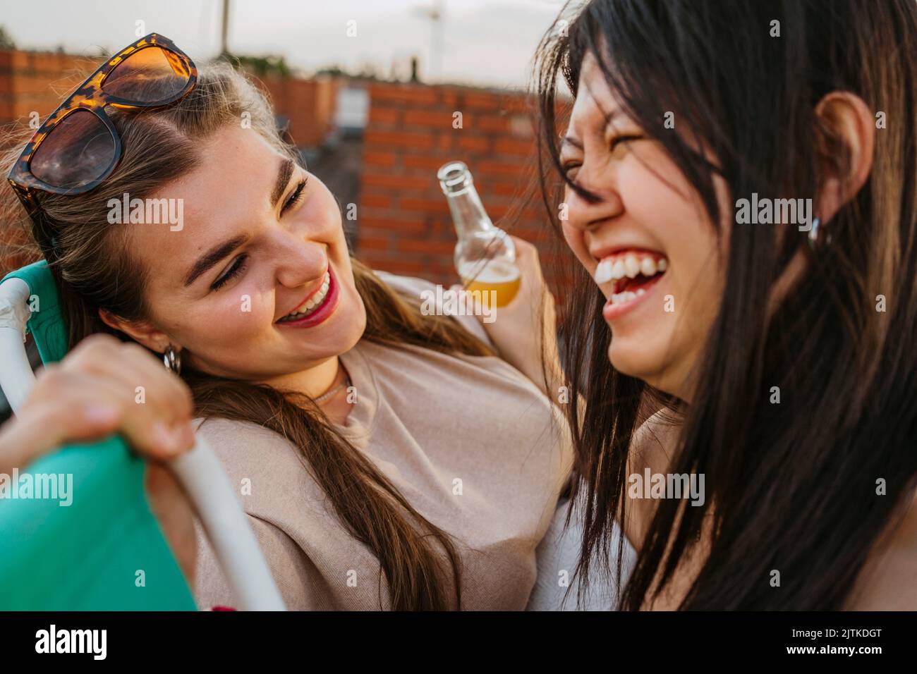 Fröhliche Frau mit Sonnenbrille und Blick auf eine Freundin, die lacht Stockfoto