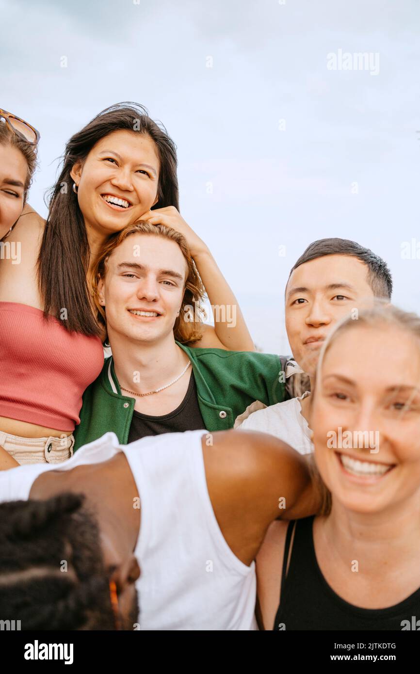 Porträt lächelnder multirassischer Freunde gegen den Himmel Stockfoto