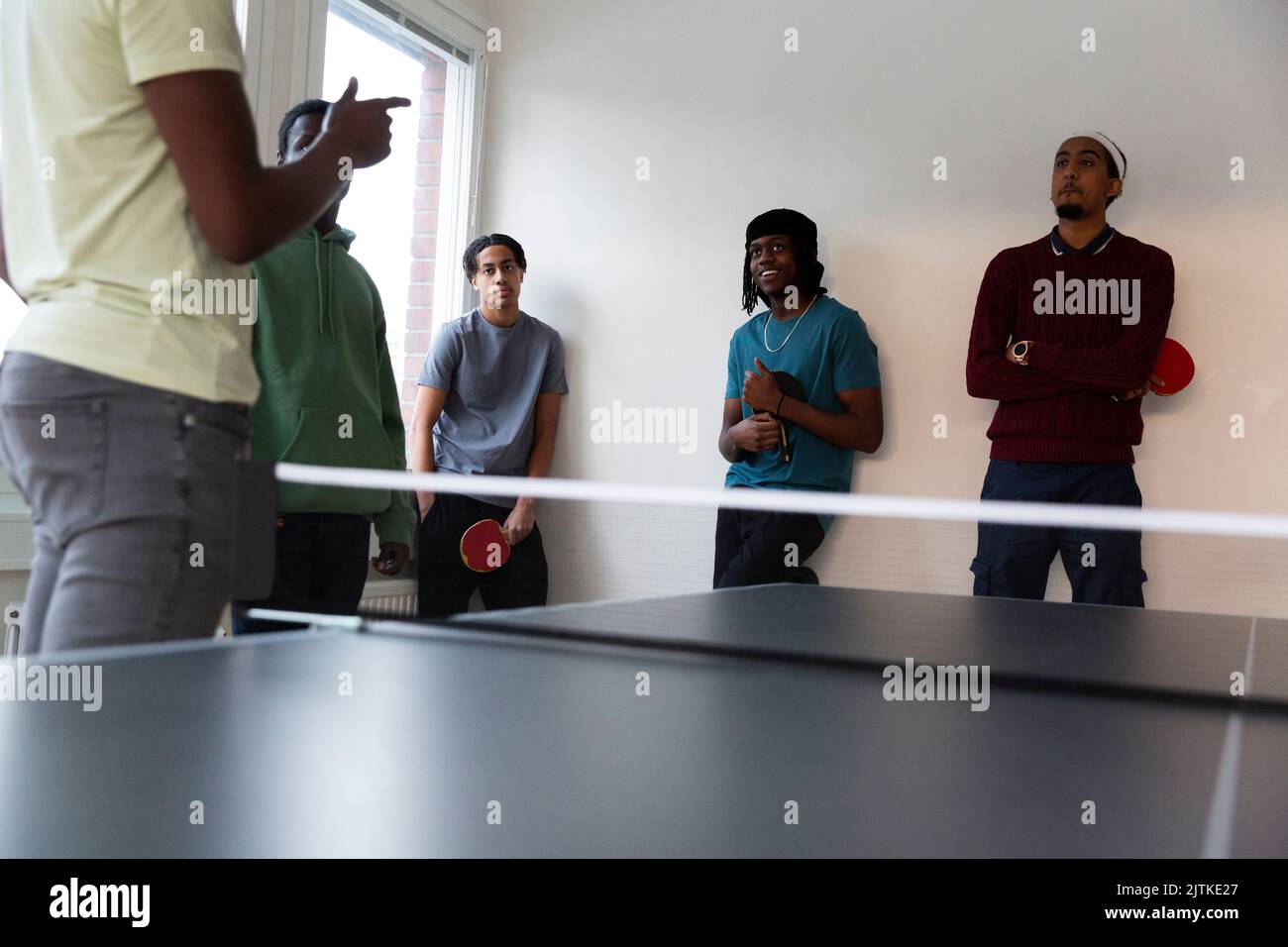 Teilnehmer an einem Tischtennistraining, das vom Trainer im Spielzimmer durchgeführt wird Stockfoto