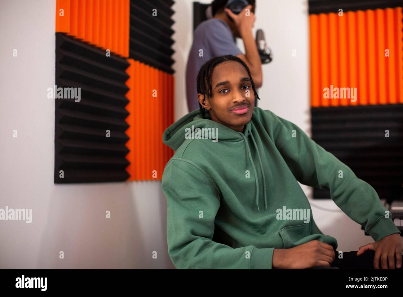 Junge mit grünem Hoodie sitzt im Aufnahmestudio Stockfoto