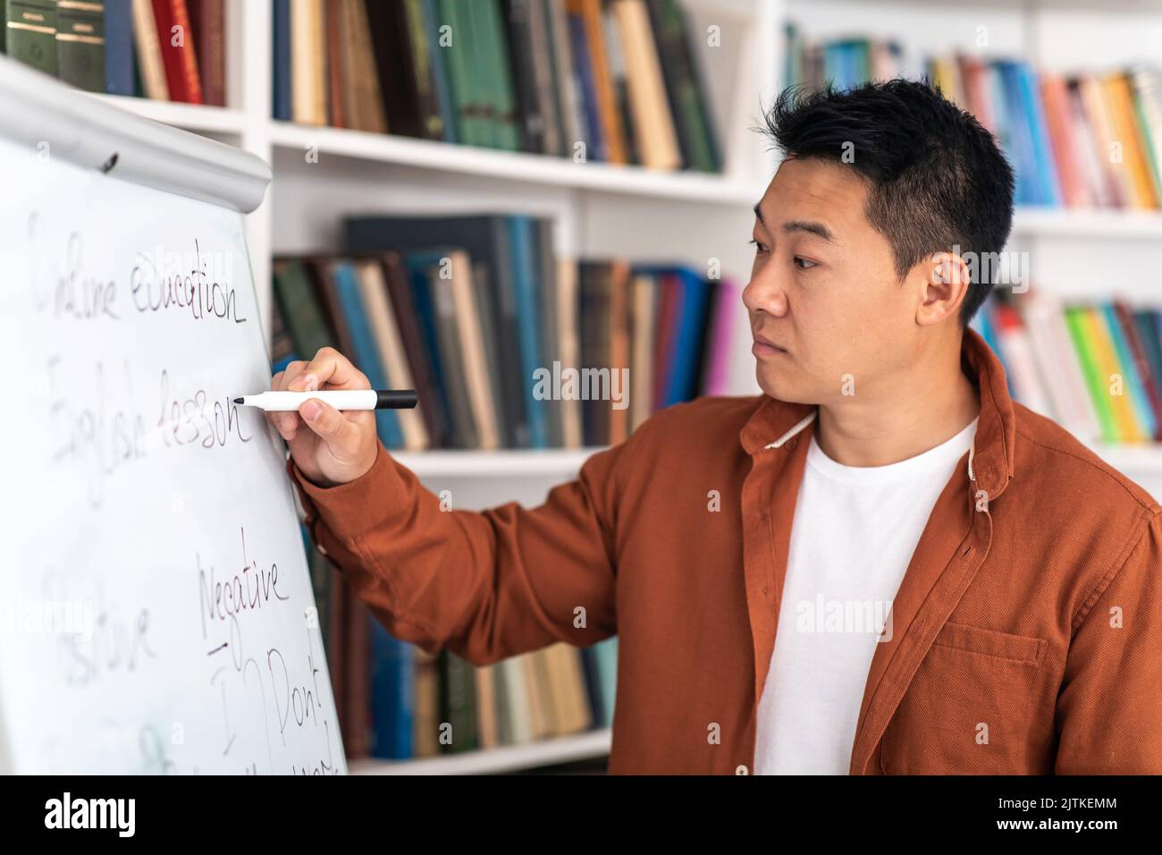 Chinesischer Männlicher Tutor, Der Auf Whiteboard Schreibt, Mit Klasse Im Klassenzimmer Stockfoto