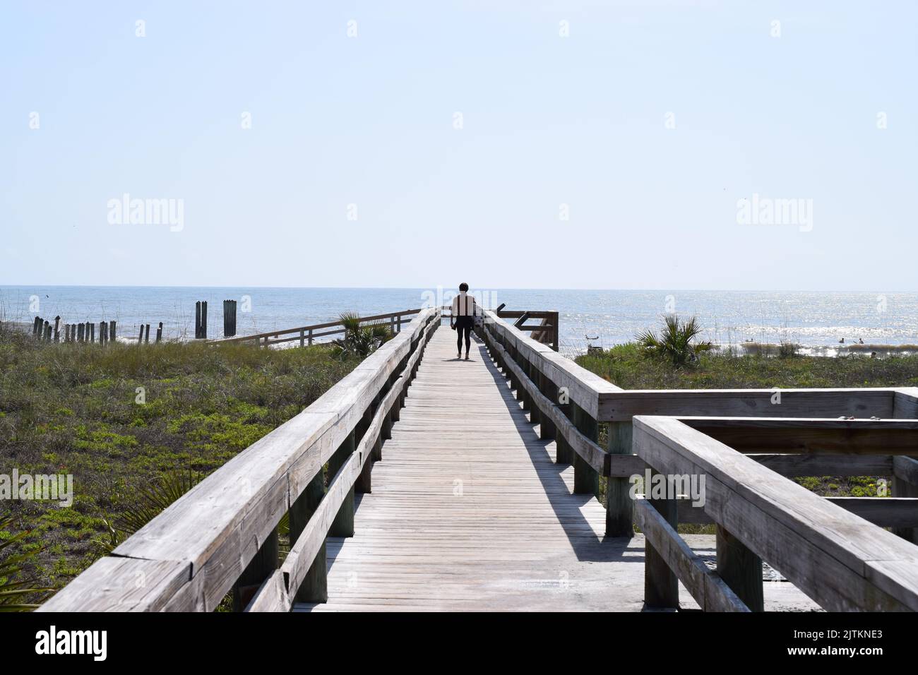 Ein Mann, der auf einer hölzernen Promenade in der Nähe des Meeres steht Stockfoto