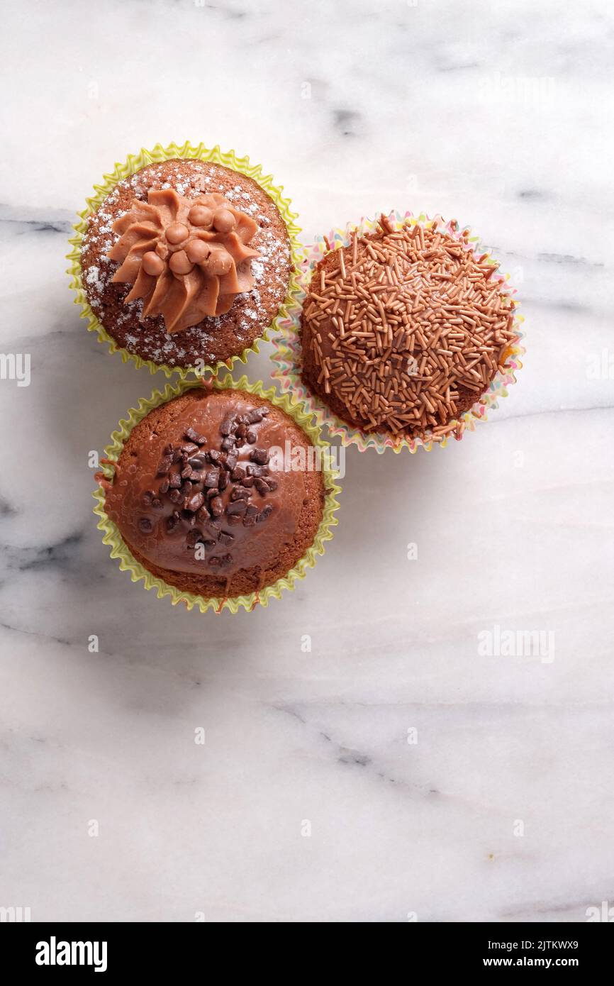 Von oben auf grauem Marmorhintergrund gedrehte Cupcakes aus Schokolade mit Platz für Kopien Stockfoto