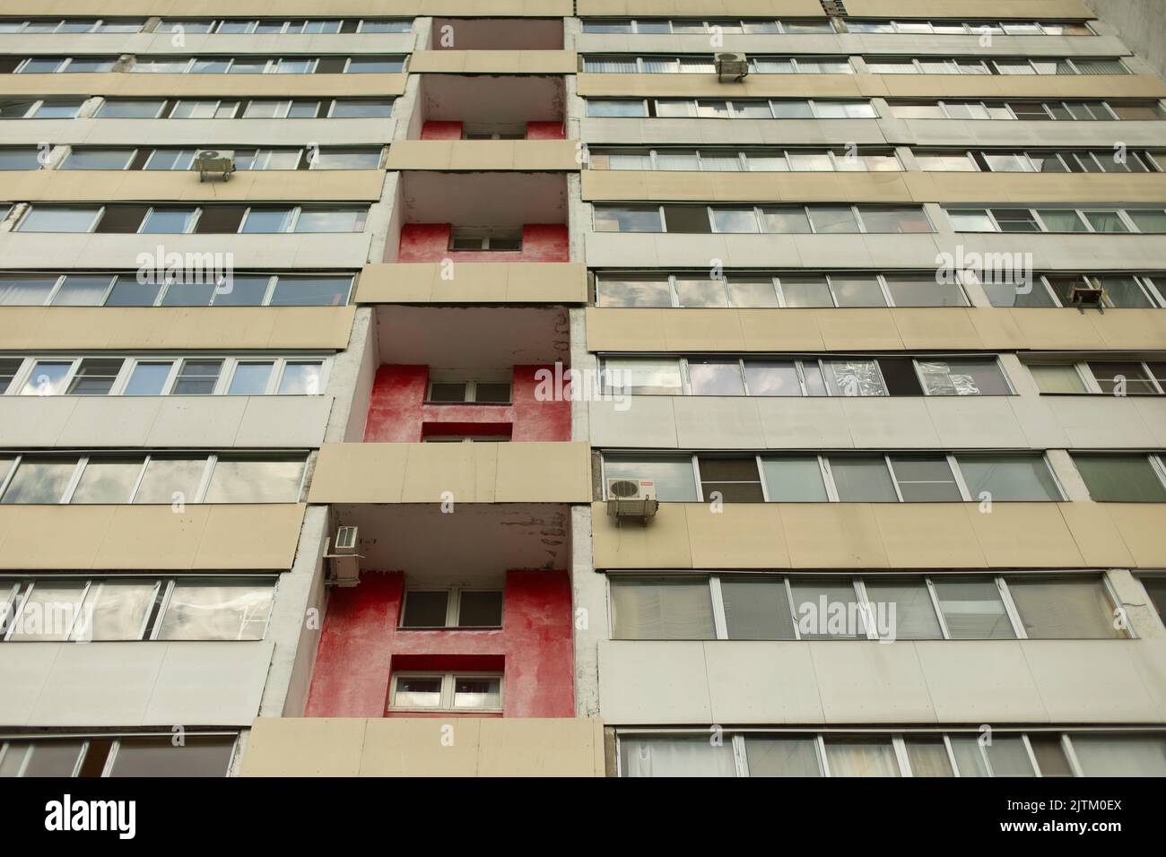 Wohnhaus mit roter Mauer. Fenster im Haus. Glas auf dem Balkon. Details der Stadt. Stockfoto