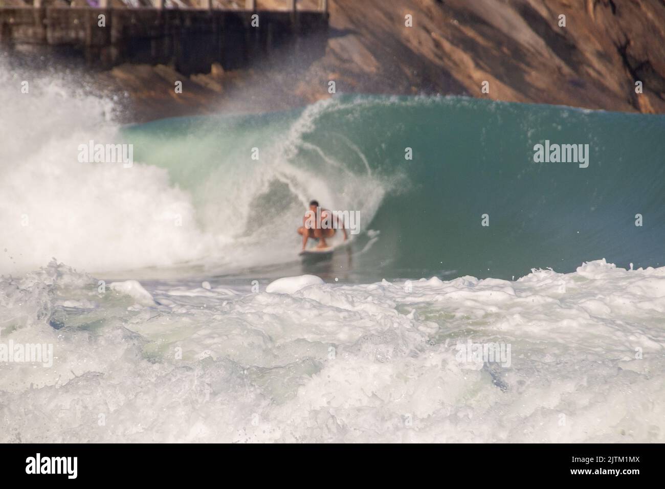 Weißer Schaum einer Welle am leblon Strand mit defokussiertem Surfer im Hintergrund in Rio de Janeiro Brasilien. Stockfoto