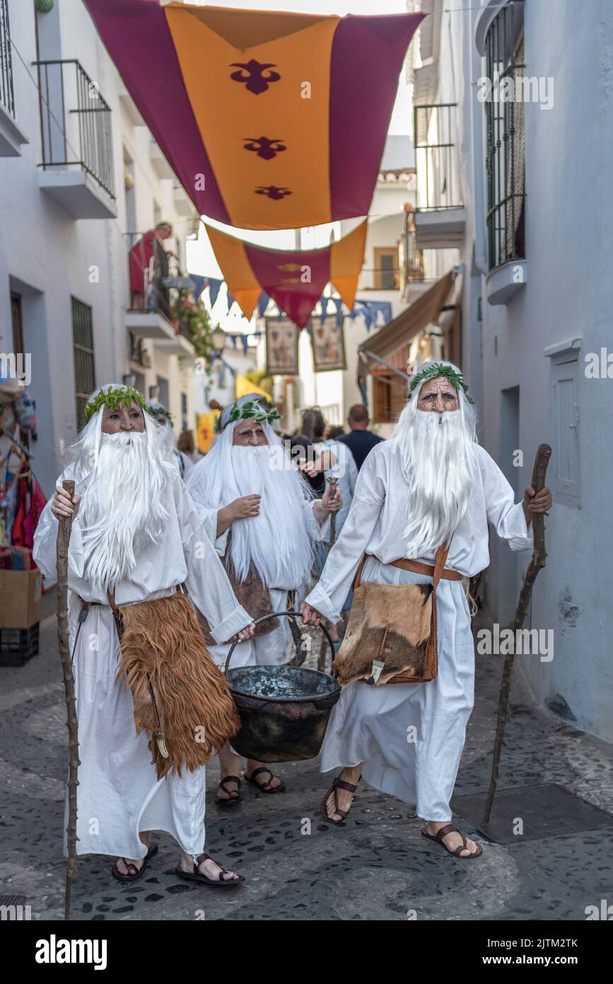 Frigiliana, Malaga, Spanien, 27. August 2022: Druiden, die als Zauberer mit Bärten und weißen Gewändern gekleidet sind und einen Kessel durch die Straßen von Frigiliana tragen Stockfoto