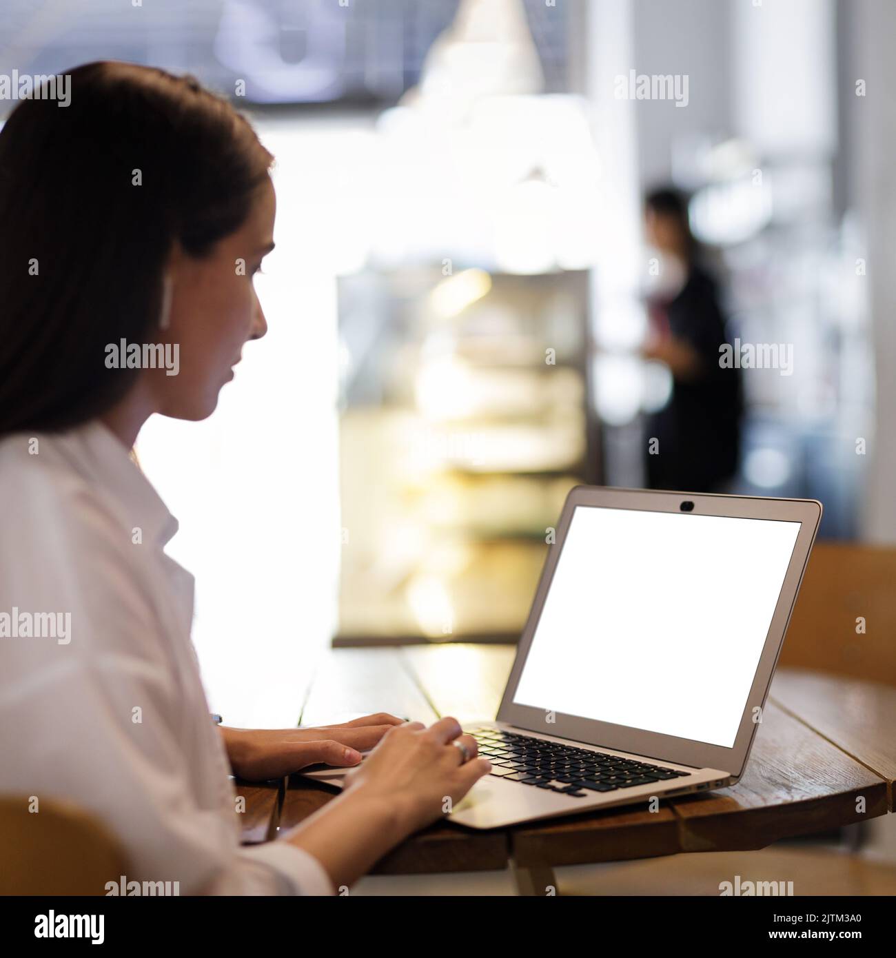 Junge hübsche Frau mit Laptop im Café. Abbildung mit leerem Bildschirm des Laptops Stockfoto
