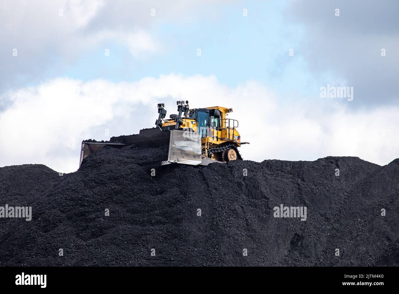 Bulldozer, der Kohle auf dem Hanasaari-Kohlevorrat in Helsinki, Finnland, anhäuft Stockfoto