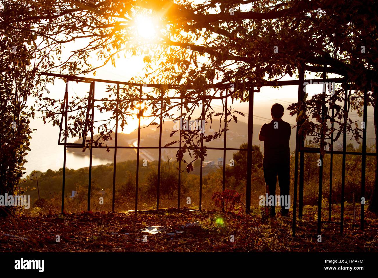 Ein denkender Mann, der den Sonnenuntergang betrachtet. Mann und Baum Silhouette in Hintergrundbeleuchtung geschossen . Mit Blick auf den Sonnenuntergang. Orange und autumn.selective Fokus. Stockfoto