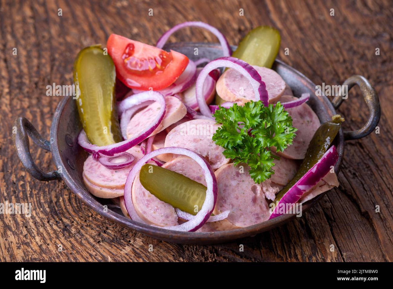 bayerischer Wurstsalat auf dunklem Holz Stockfoto