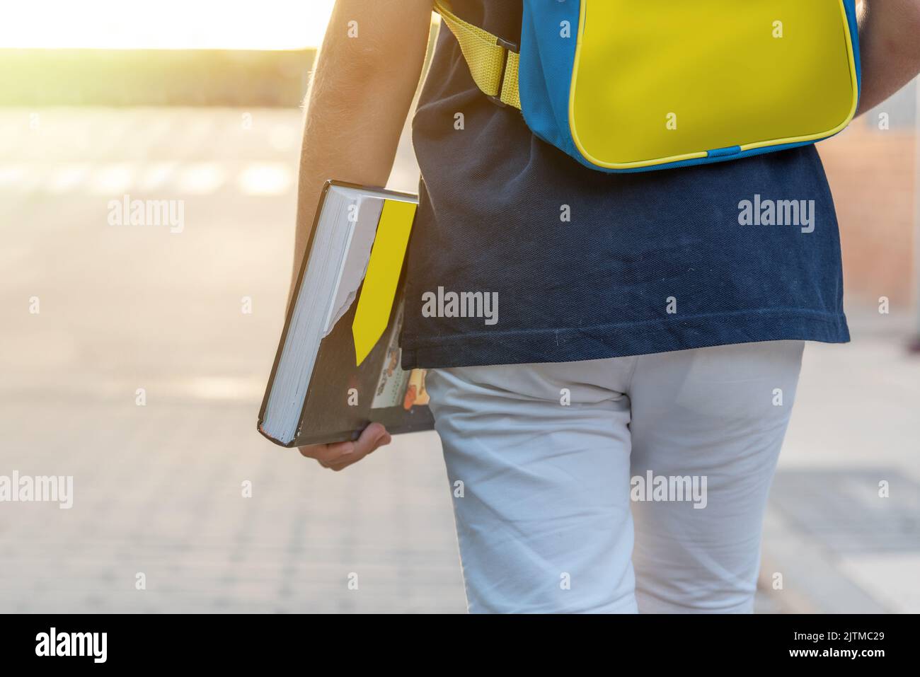 Nahaufnahme eines Jungen auf der Straße mit einem Rucksack in den Farben der ukrainischen Flagge gelb und blau und einem Buch in der Hand. Zurück zur Schule Stockfoto