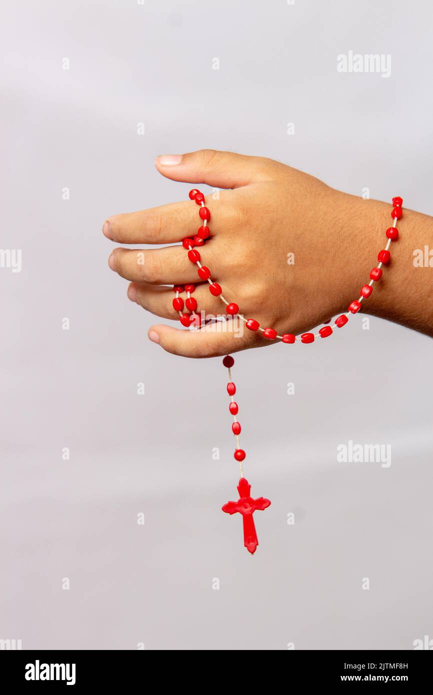 Hand eines Kindes mit einem roten Rosenkranz in der Hand in Brasilien. Stockfoto