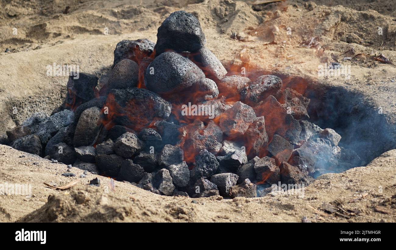 Heiße Kohlen und Steine schwelen, als die imu für ein Luau auf Hawaii vorbereitet wird. Stockfoto