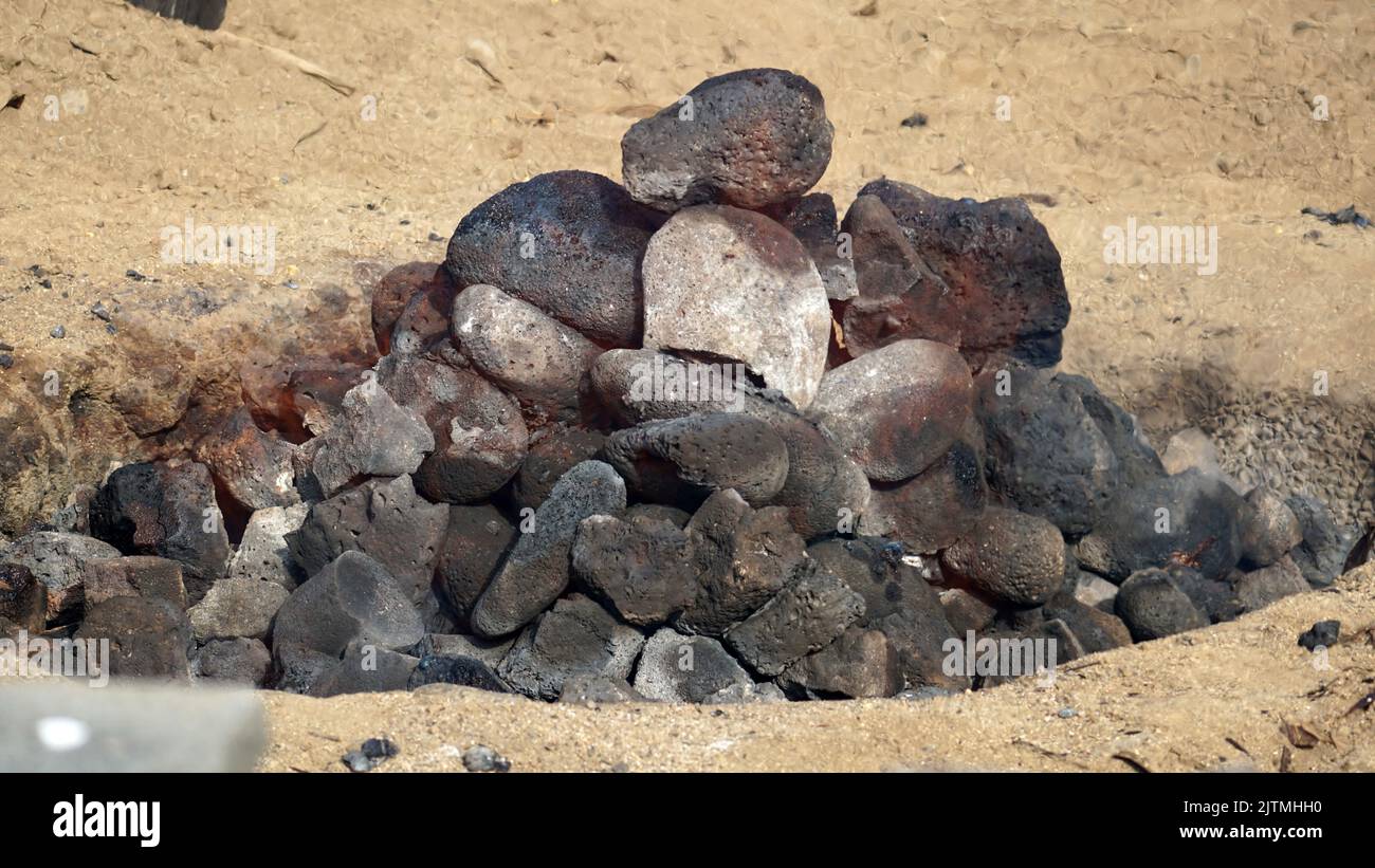 Heiße Kohlen und Steine schwelen, als die imu für ein Luau auf Hawaii vorbereitet wird. Stockfoto