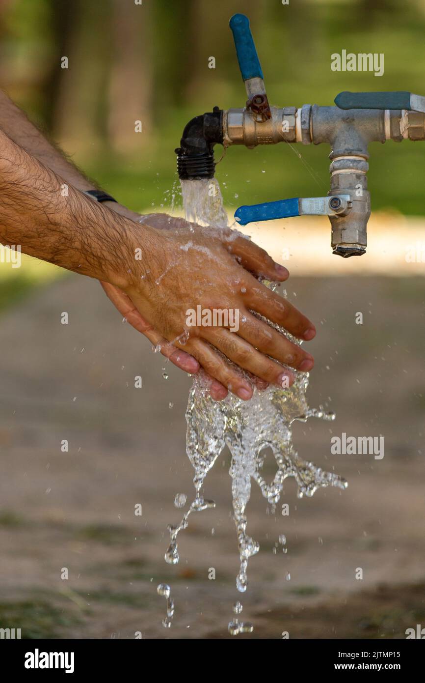 Mann wäscht sich die Hände am Brunnen. Stockfoto