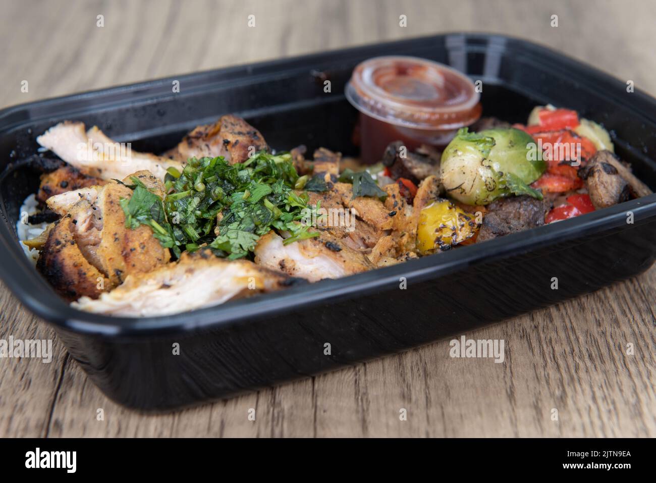 Die Bestellung von Shawarma-Huhn mit jasmin-Reis ist bequem in einem mikrowellenfähigen Behälter verpackt. Stockfoto