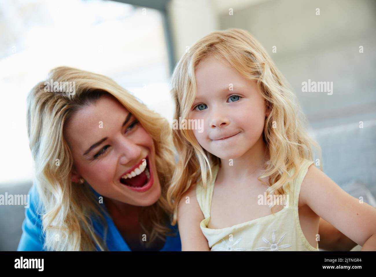 Genießen Sie jeden Moment mit ihrer Tochter. Eine junge Mutter und ihre Tochter lachen, während sie zu Hause auf dem Sofa sitzen. Stockfoto