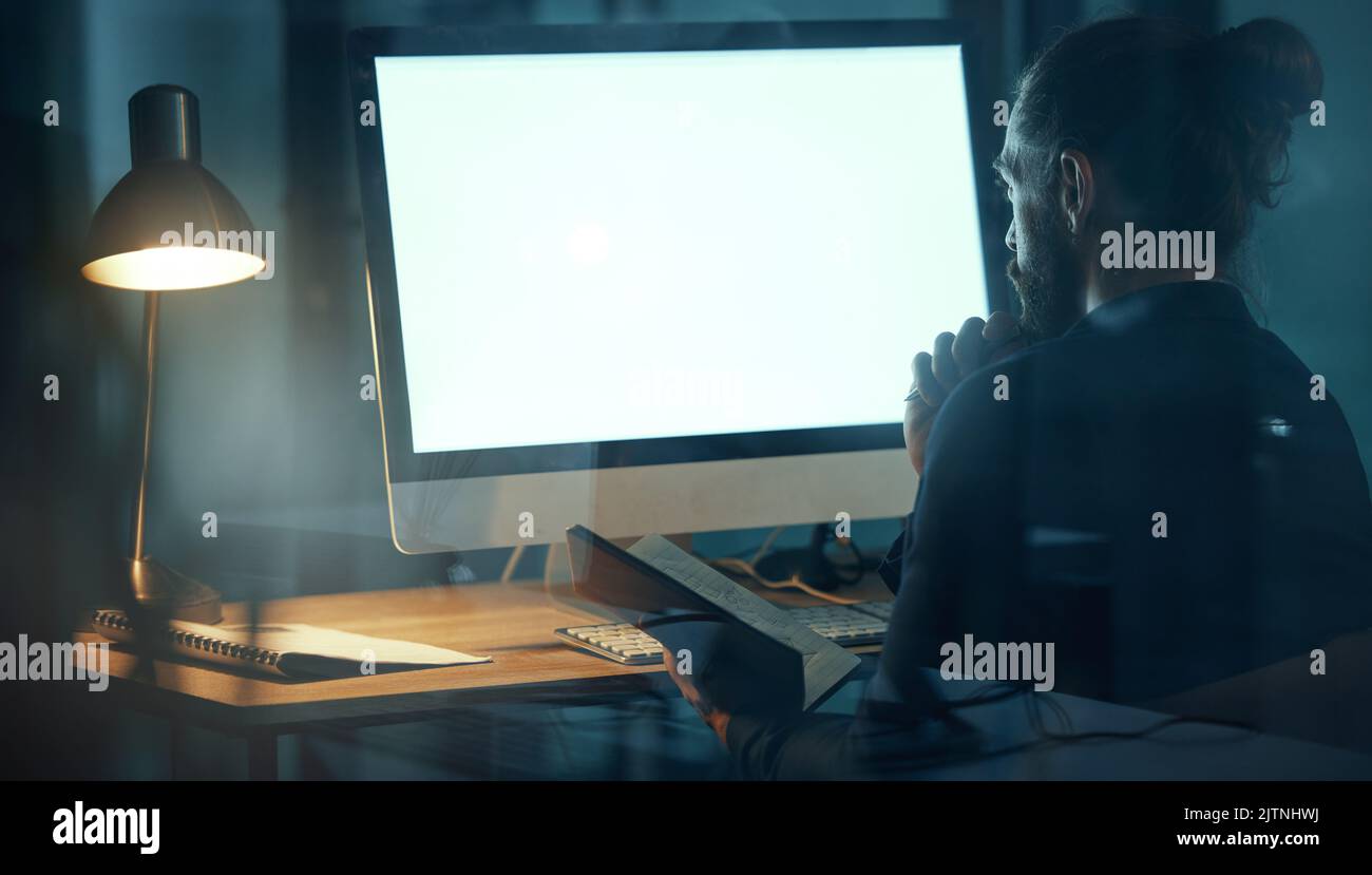 Ein Geschäftsmann, der Webdesign am Computer bei der Arbeit macht, Designer, der eine Website online plant und in einem dunklen Büro nachts an einer Werbestrategie arbeitet Stockfoto