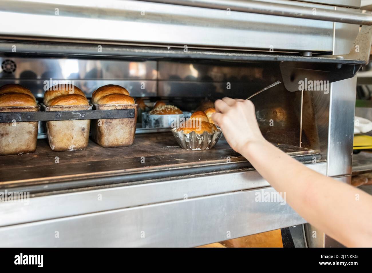Der Bäcker misst die Temperatur innerhalb der Brioche, um die Bereitschaft des Brotes zu bestimmen. Vorderansicht. Stockfoto