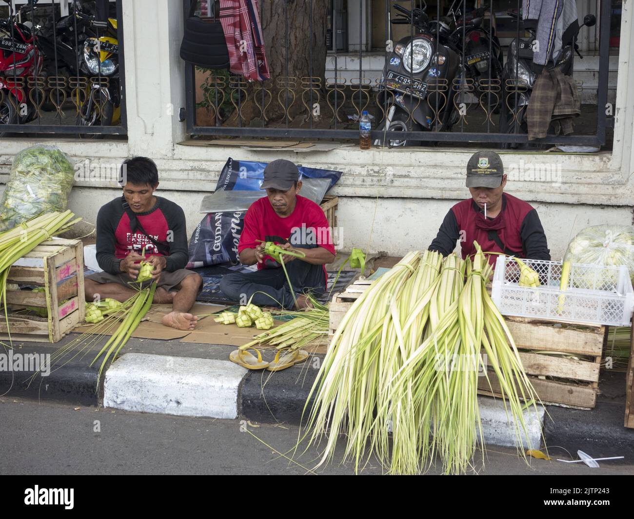 Jakarta, Indonesien-5. Juli 2022: Ketupat-Händler machen Ketupat am Straßenrand. Ketupat oder Tipat ist ein javanesischer Reiskuchen, der in einem Diamantschapf verpackt ist Stockfoto