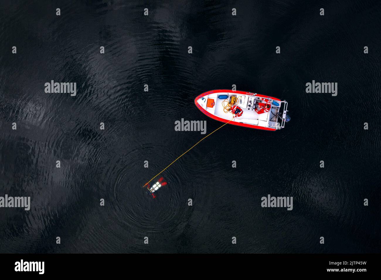 Luftaufnahme eines Tauchers an einem Seil, geführt von einem Instruktor auf einem Boot. Stockfoto