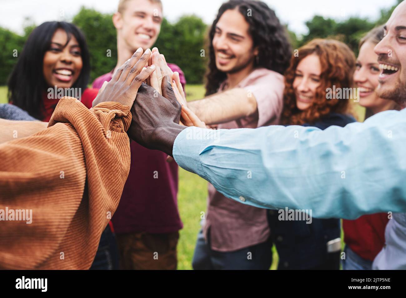 Eine Gruppe von multiethnischen jungen erwachsenen Freunden, die sich zusammenschließen und die Hände unter den hohen fünf im Freien in der Natur zusammenbringen - Menschen Teamwork Integration, Taucher Stockfoto