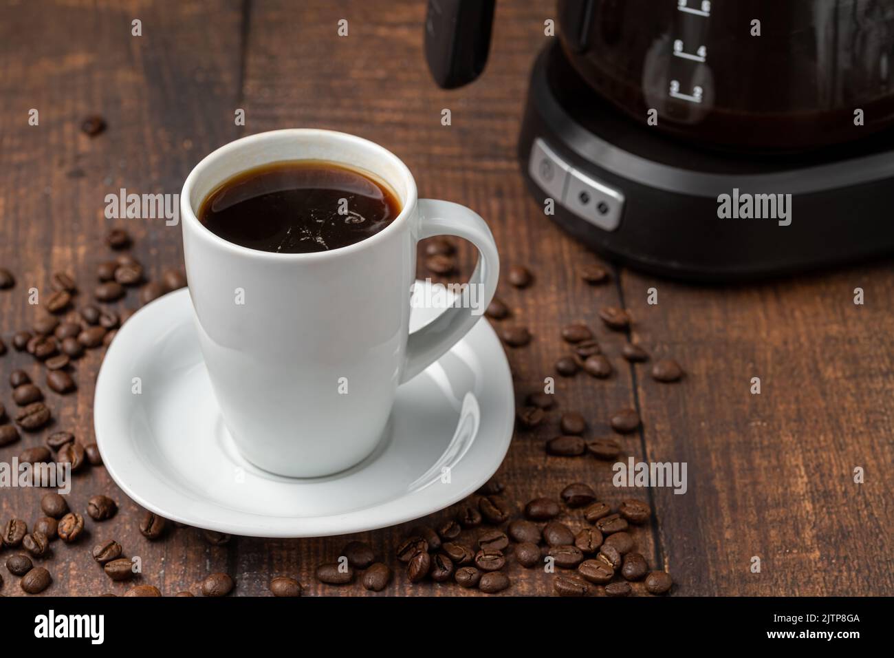 Filterkaffee, der in einer Filterkaffeemaschine in einer weißen Porzellanschale gebrüht wird Stockfoto