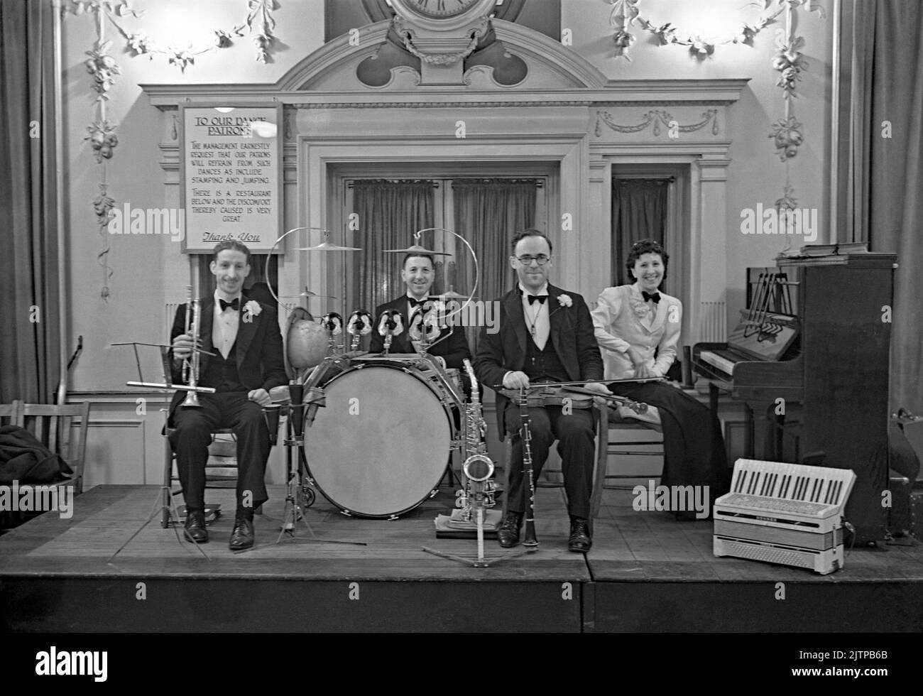 Eine britische vierköpfige Tanzband mit Mitgliedern des De Berrys Trios spielt 1939 in einem Londoner Hotel, England, bei einem Wohltätigkeitstanz zugunsten des NSPCC (National Society for the Prevention of Cruelty to Children). Das Schild hinter der Band fordert, dass Tänzer ‘Stampfen und Springen’ unterlassen sollten. Frühe Tanz- und Swing-Bands hatten ihre Blütezeit in Großbritannien während der Jahre 1920s–30s. Bands spielten in Tanzsälen und Hotelballsälen. Sie spielten melodische, gute-Zeit-Musik und einzelne Spieler spielten in mehreren Bands. Dieses Bild stammt aus einem alten Glas-Negativ – einem Vintage-Foto aus dem Jahr 1930s. Stockfoto