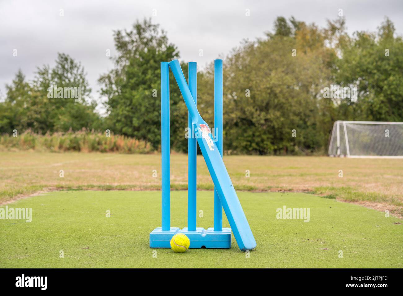 Nahaufnahme von blauen Cricketstümpfen, blauem Cricketschläger und gelbem Tennisball im Freien, bereit für eine Junior-Version des Spiels für Kinder. Stockfoto