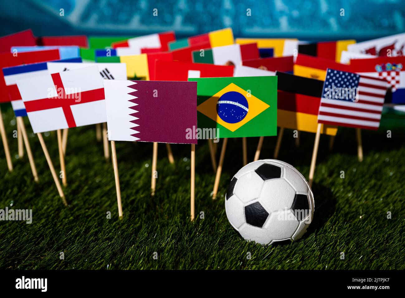 Fußballhintergrund. Fußball auf grünem Gras und 32 Flaggen, die in Katar am 2022. Dezember spielen wird Stockfoto