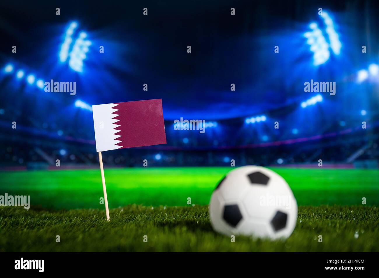 Qatar National Flag auf Green Grass des beleuchteten Fußballstadions in der Nacht Stockfoto
