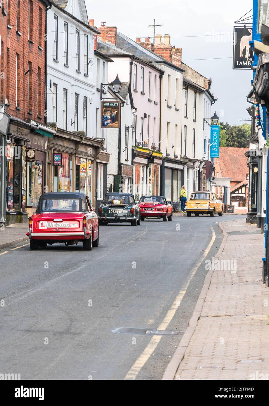 Ein Konvoi von vier Triumph-Autos auf dem Weg entlang der High Street zur Kington Vintage Show, Herefordshire England, Großbritannien, August 2022 Stockfoto